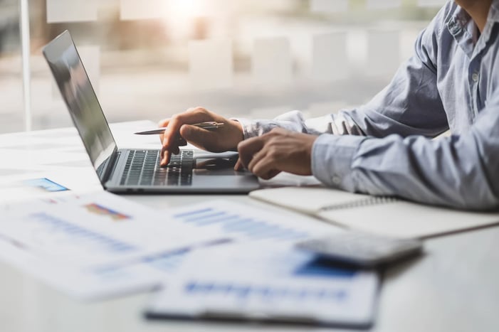 banking technology on a laptop with printed out spreadsheets