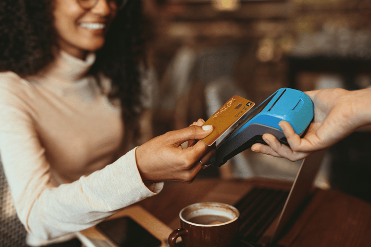 woman making a contactless payment in a cafe at a table